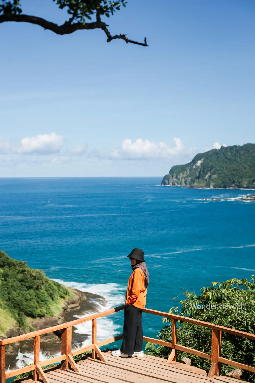 Seorang wisatawan menikmati pemandangan laut biru dari deck kayu di Green Island Banyuwangi.
