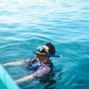 Seorang wisatawan mengapung dengan pelampung sambil memakai snorkel di perairan Menjangan.